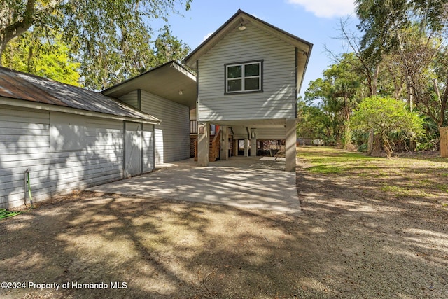 rear view of property with a carport and an outbuilding