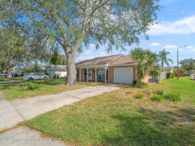 ranch-style home with covered porch, a garage, and a front yard