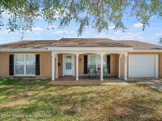 single story home featuring a garage, a porch, and a front lawn