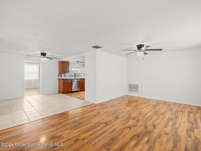 unfurnished living room with ceiling fan, a textured ceiling, and light wood-type flooring