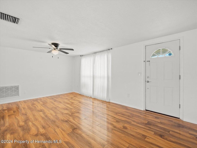 foyer entrance with ceiling fan, wood-type flooring, a healthy amount of sunlight, and a textured ceiling