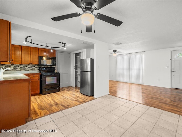 kitchen featuring decorative backsplash, light hardwood / wood-style floors, black appliances, and a healthy amount of sunlight