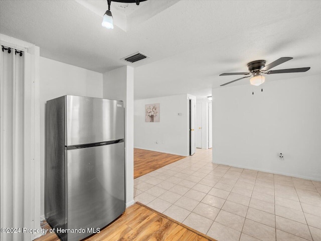 kitchen featuring ceiling fan, a textured ceiling, stainless steel refrigerator, and light hardwood / wood-style floors