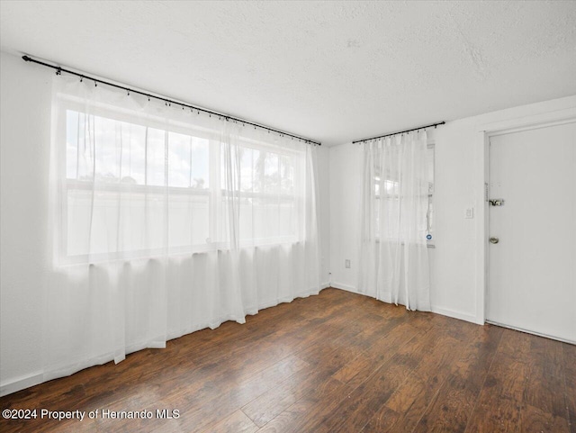 unfurnished room with a textured ceiling, dark hardwood / wood-style floors, and plenty of natural light