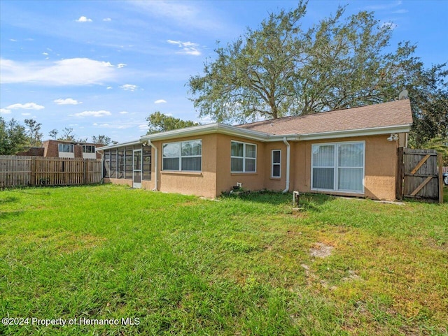 rear view of house featuring a lawn and a sunroom