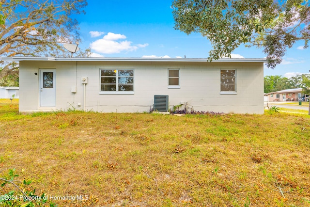 back of property with central air condition unit and a lawn