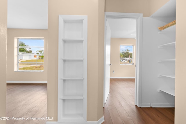 hallway with a wealth of natural light, wood-type flooring, and built in shelves