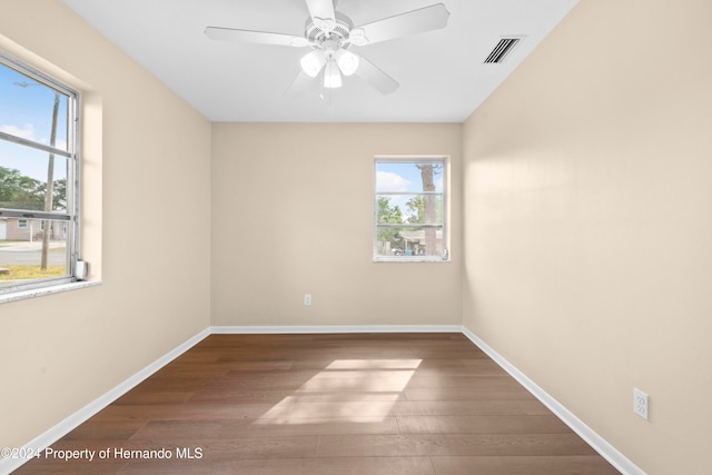 unfurnished room featuring dark wood-type flooring, a healthy amount of sunlight, and ceiling fan