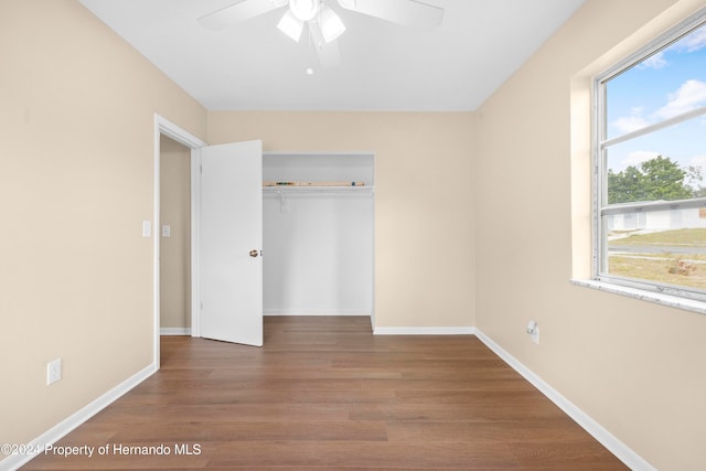 unfurnished bedroom featuring hardwood / wood-style floors, ceiling fan, and a closet