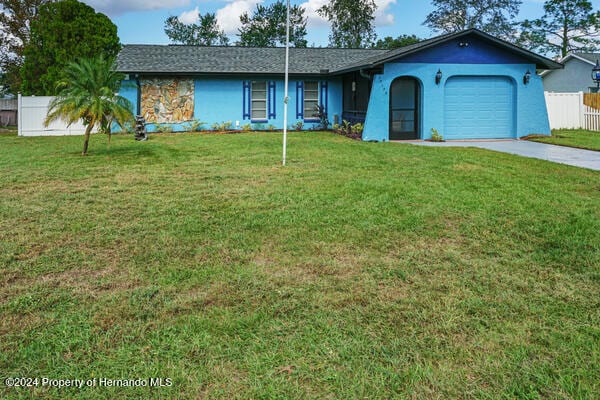 ranch-style house with a garage and a front lawn