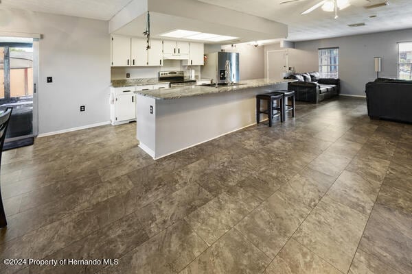 kitchen with white cabinets, appliances with stainless steel finishes, ceiling fan, and a center island