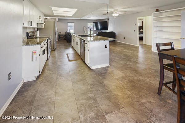 kitchen with white cabinetry, stainless steel appliances, sink, and dark stone countertops