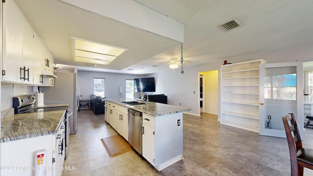 kitchen featuring a center island, sink, stone counters, white cabinetry, and appliances with stainless steel finishes