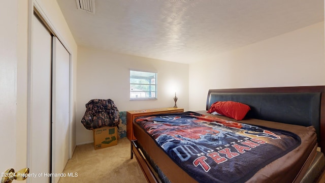 carpeted bedroom with a closet and a textured ceiling