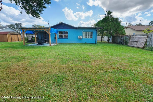 back of house featuring a storage unit, a patio, a pergola, and a yard