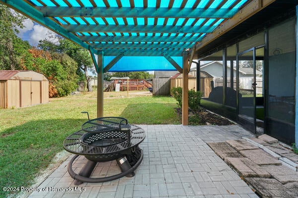 view of patio featuring a playground, a fire pit, and a shed