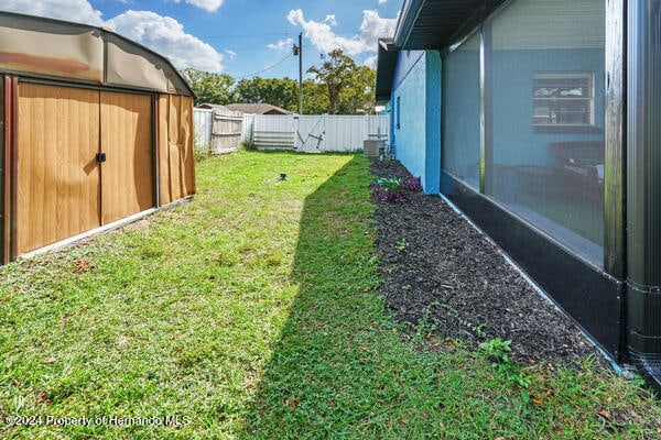 view of yard with central air condition unit and a shed