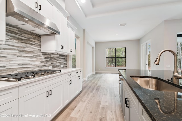 kitchen featuring white cabinetry, sink, dark stone countertops, appliances with stainless steel finishes, and light wood-type flooring