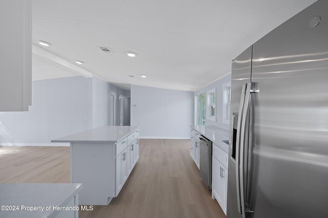 kitchen with white cabinets, a kitchen island, appliances with stainless steel finishes, and light hardwood / wood-style flooring