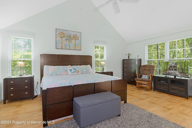 bedroom with high vaulted ceiling, ceiling fan, multiple windows, and light hardwood / wood-style floors