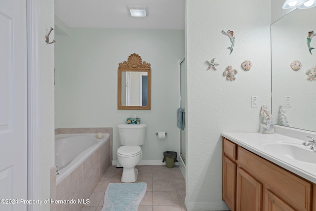 bathroom with tiled tub, tile patterned flooring, vanity, and toilet