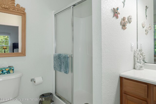 bathroom featuring vanity, an enclosed shower, and toilet