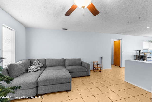 living room with light tile patterned floors, a textured ceiling, and ceiling fan