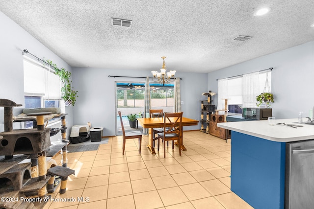 tiled dining room featuring a healthy amount of sunlight, a textured ceiling, and an inviting chandelier