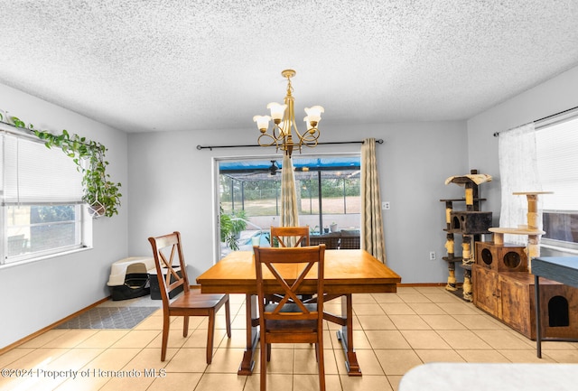 tiled dining room with a notable chandelier, a healthy amount of sunlight, and a textured ceiling