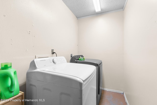 clothes washing area with washing machine and clothes dryer and a textured ceiling