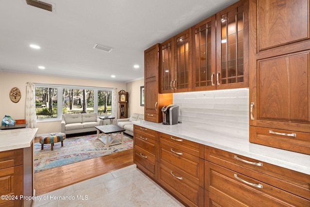 kitchen with light wood-type flooring, ornamental molding, and tasteful backsplash