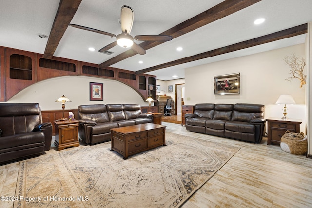 living room featuring ceiling fan, beamed ceiling, and light wood-type flooring