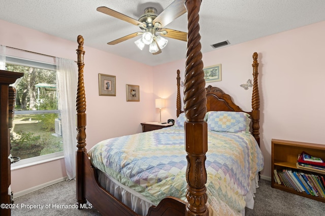 bedroom with ceiling fan, light colored carpet, and a textured ceiling