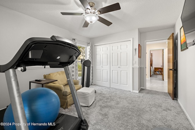 workout room featuring a textured ceiling, light colored carpet, and ceiling fan