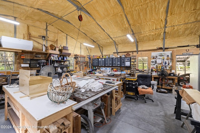 misc room with concrete flooring, a workshop area, and lofted ceiling