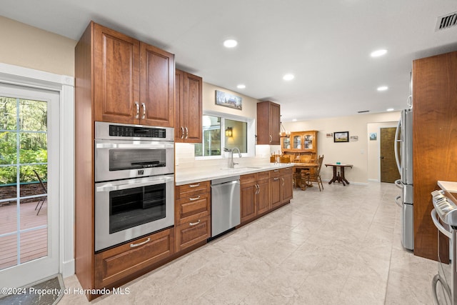 kitchen featuring appliances with stainless steel finishes, backsplash, plenty of natural light, and sink