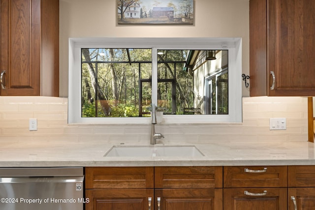 kitchen with tasteful backsplash, light stone countertops, sink, and stainless steel dishwasher