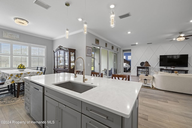 kitchen featuring crown molding, sink, pendant lighting, a center island with sink, and dishwasher