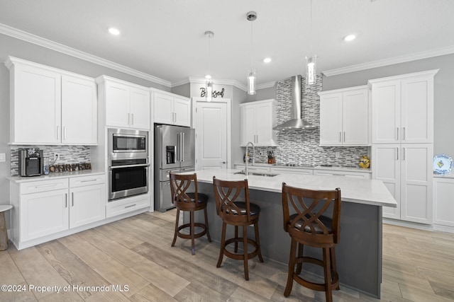 kitchen featuring white cabinets, appliances with stainless steel finishes, hanging light fixtures, and wall chimney range hood