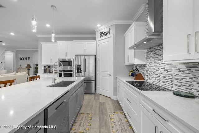 kitchen with white cabinets, light wood-type flooring, wall chimney range hood, and appliances with stainless steel finishes