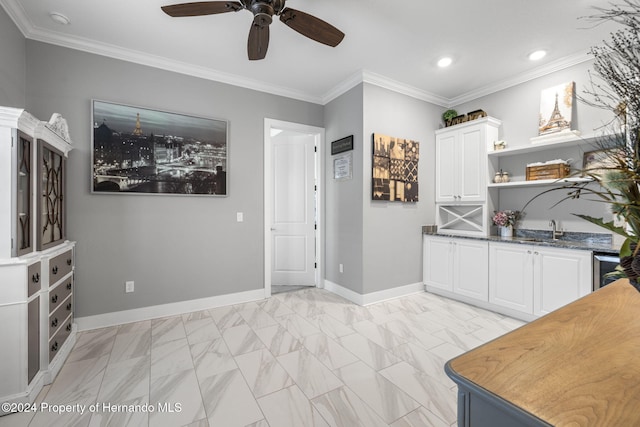 kitchen featuring white cabinets, sink, ceiling fan, dark stone countertops, and ornamental molding