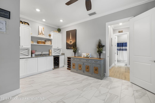 bar featuring ceiling fan, sink, beverage cooler, white cabinets, and ornamental molding