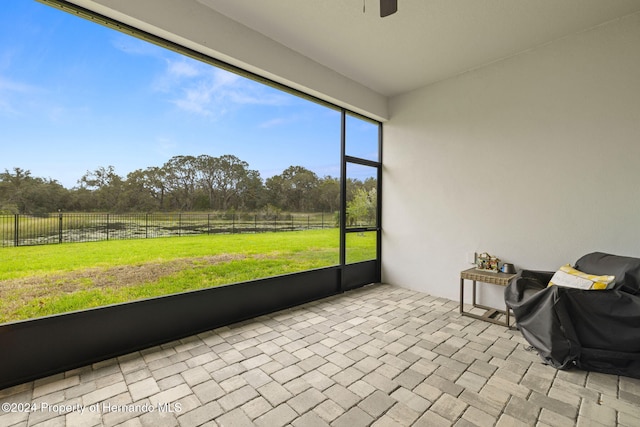 unfurnished sunroom featuring a rural view and ceiling fan