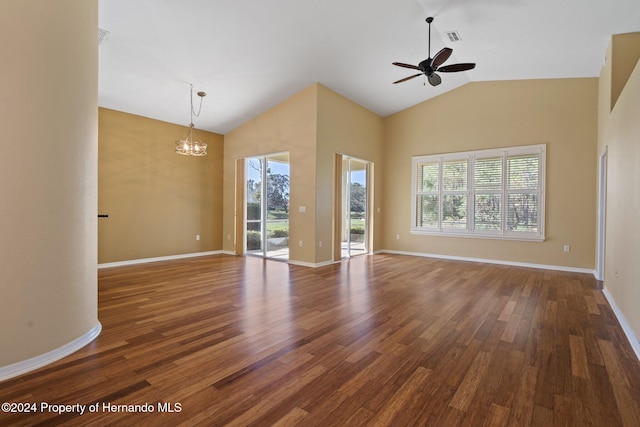 unfurnished living room with ceiling fan with notable chandelier, dark hardwood / wood-style flooring, and vaulted ceiling