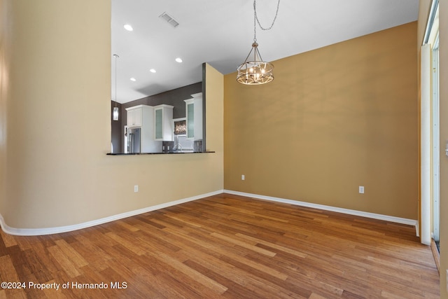 unfurnished dining area featuring a notable chandelier and light hardwood / wood-style floors