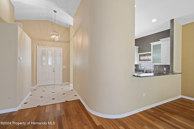 entrance foyer featuring wood-type flooring, vaulted ceiling, and an inviting chandelier