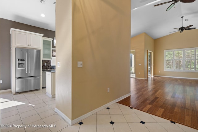 kitchen featuring stainless steel appliances, light tile patterned floors, lofted ceiling, decorative backsplash, and white cabinets