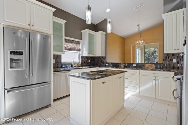 kitchen featuring appliances with stainless steel finishes, a center island, vaulted ceiling, and backsplash