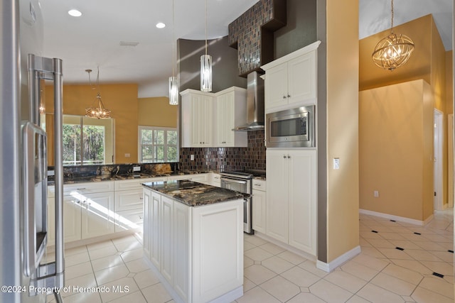 kitchen with pendant lighting, a center island, wall chimney exhaust hood, appliances with stainless steel finishes, and tasteful backsplash