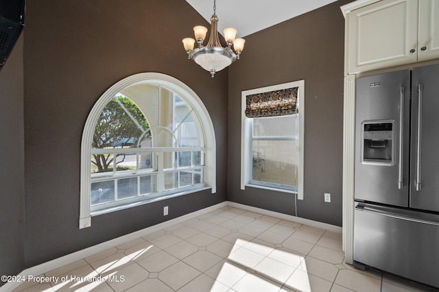 unfurnished dining area with light tile patterned floors, lofted ceiling, and a notable chandelier